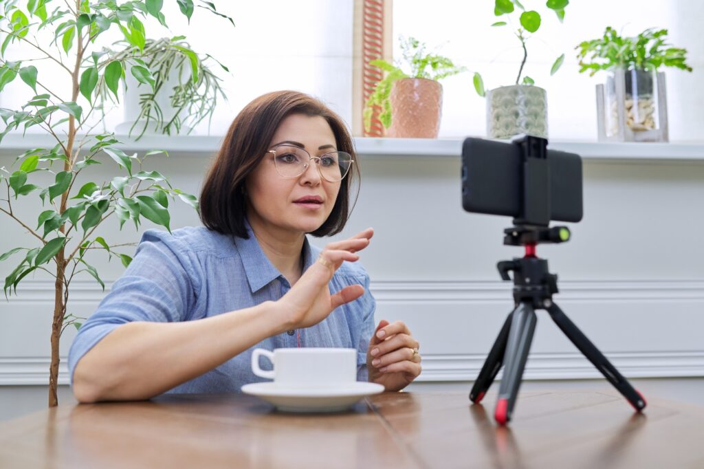 Woman teacher, mentor, psychologist looking at webcam of smartphone